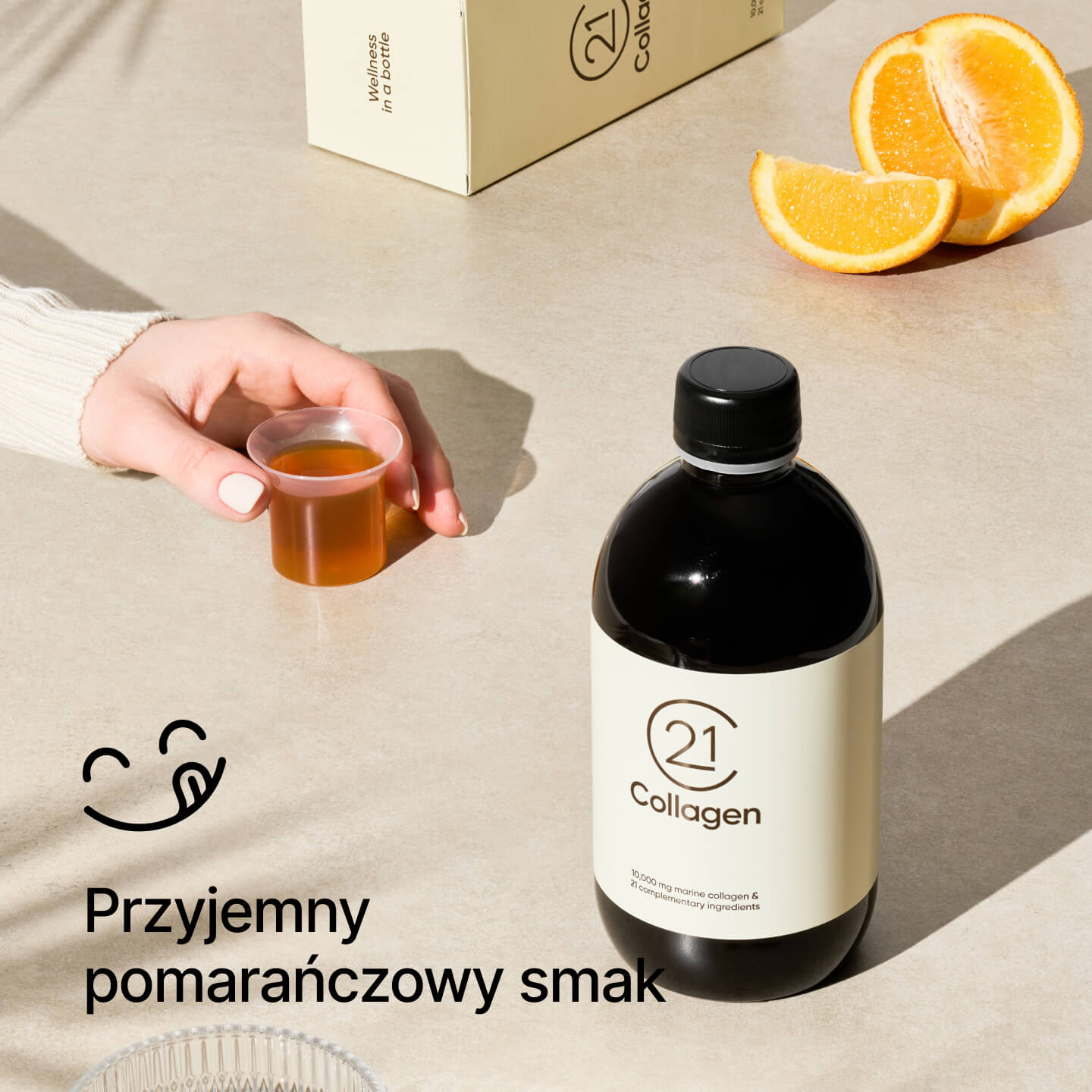 Ręka trzyma dzienną porcję 21Collagen o smaku pomarańczowym; butelka, pudełko i plasterki pomarańczy w tle, tekst: „Przyjemny smak pomarańczy”.